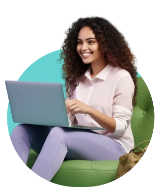 A woman with curly hair sits on a green chair, working on a laptop in a pink blouse and purple pants, smiling against a teal background.