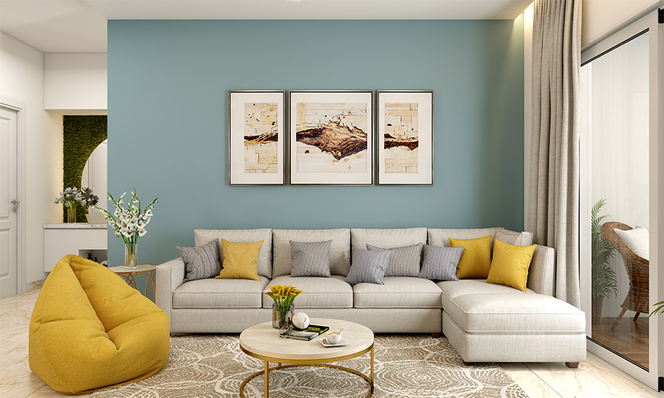 A contemporary living room includes a gray sectional sofa with yellow cushions, abstract art, a round coffee table, a yellow beanbag, and a sliding glass door.